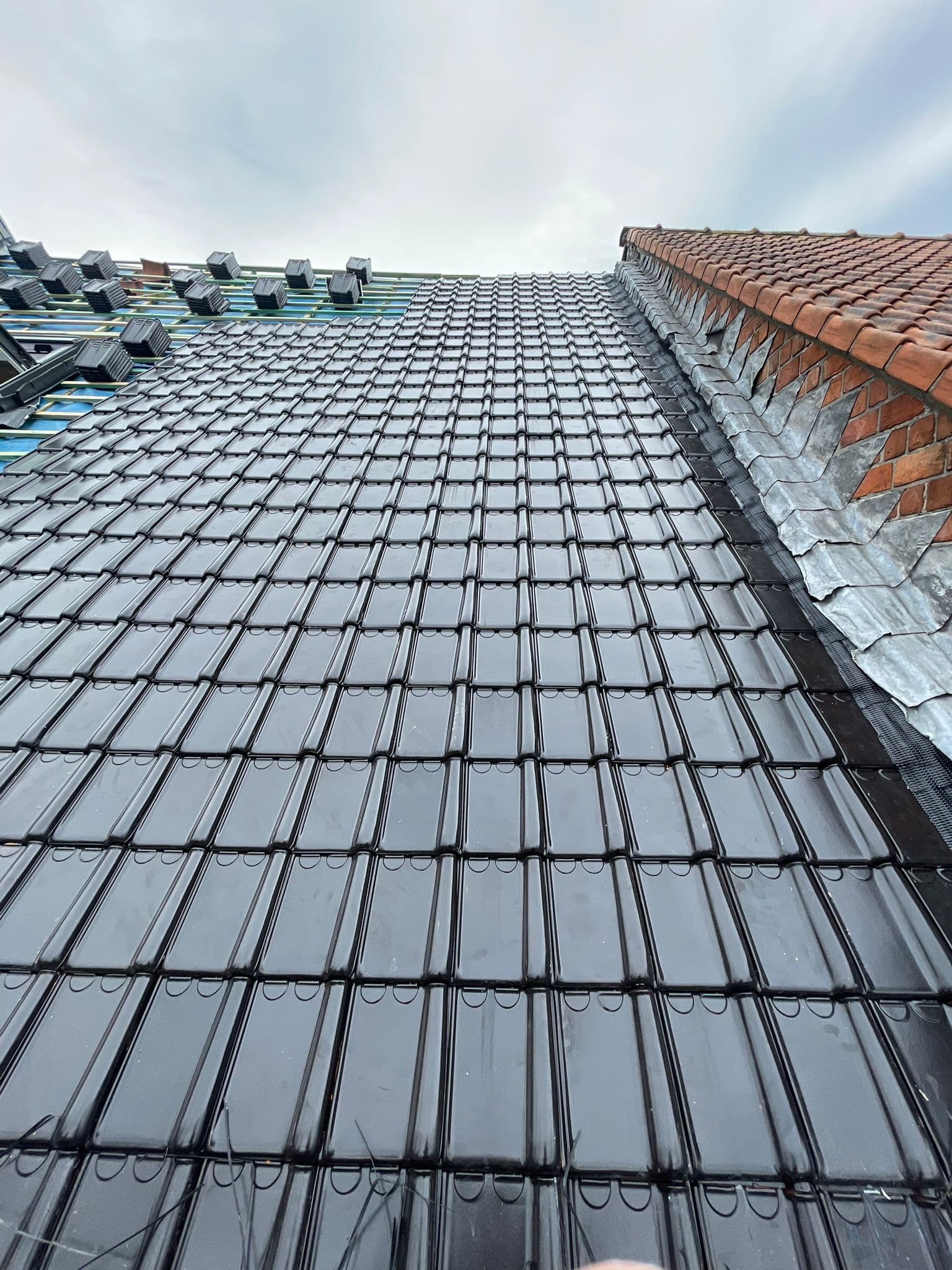 Plaatsing zwarte dakpannen op hellend dak